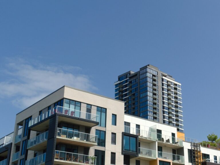 Modern condominium buildings with glass balconies against a blue sky, representing presale condo purchases in BC.